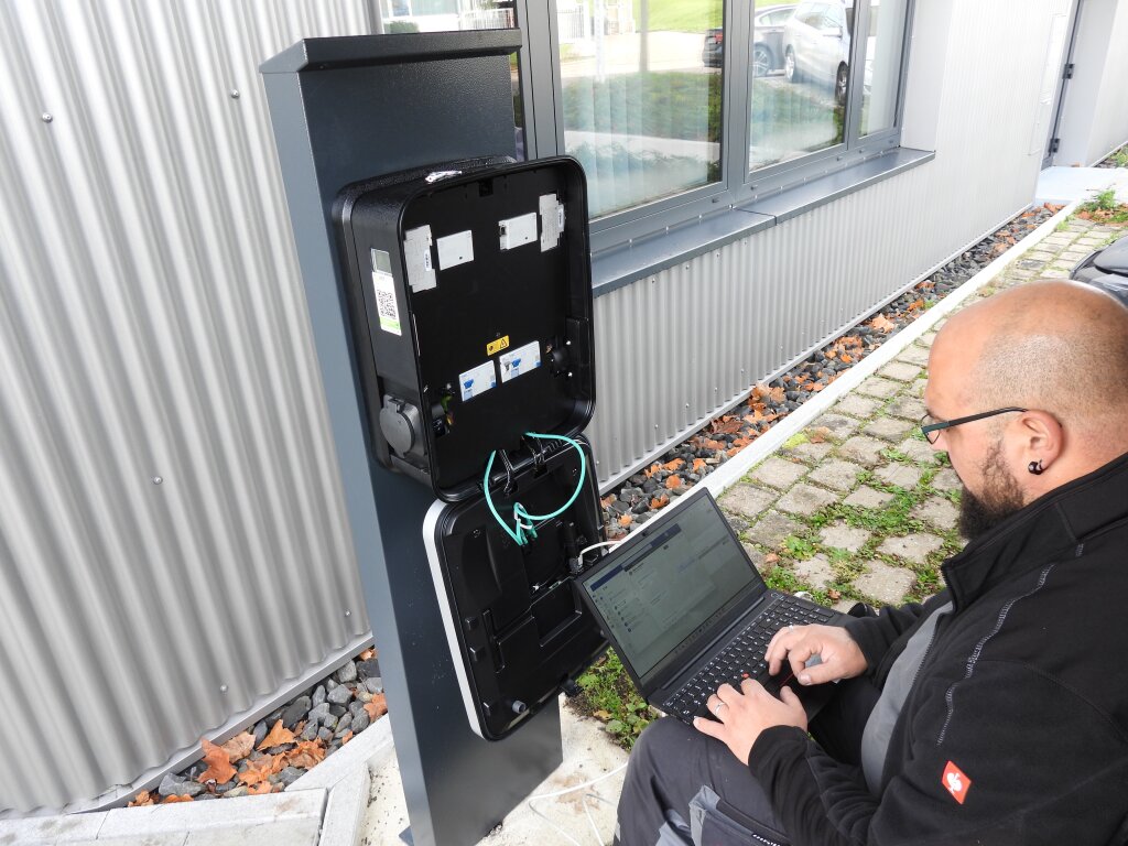 Ein Techniker beim Konfigurieren einer Ladestationsbox mit seinem Laptop.