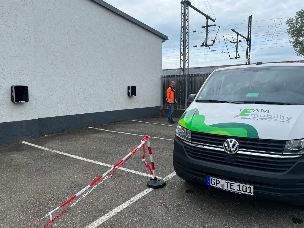Ein Techniker neben einem Sprinter und Parkplatzwallboxen.